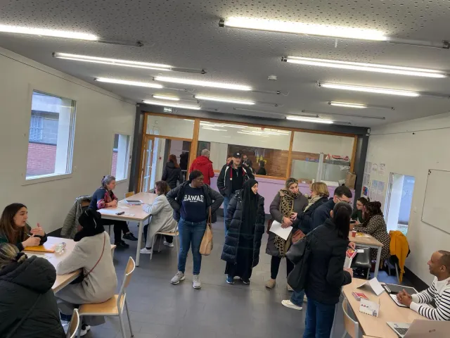 Forum emploi dans la grande salle du Centre : habitants et recruteurs échangent autour des tables.