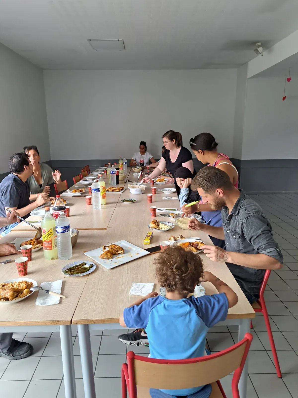 Adultes et enfants réunis autour d’une table pour un repas partagé au Centre