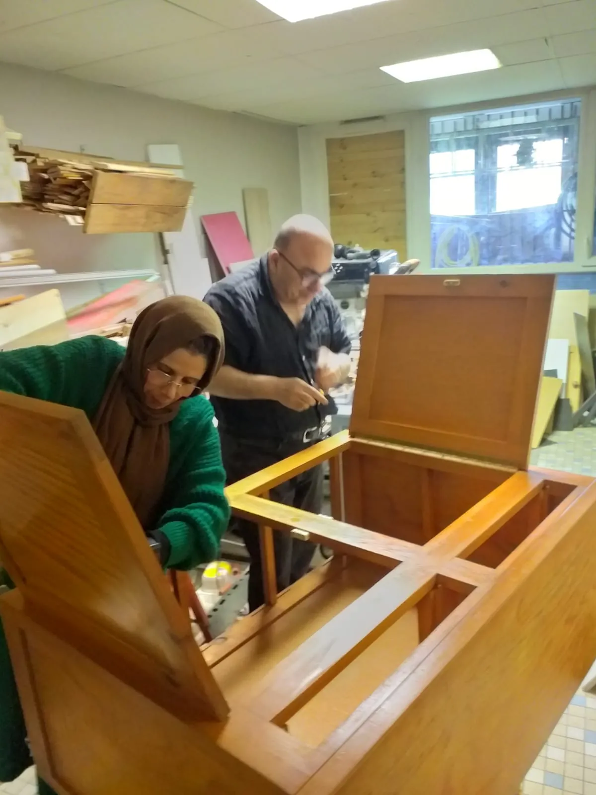 Une participante et un animateur restaurent un meuble à l’atelier Éco-brico