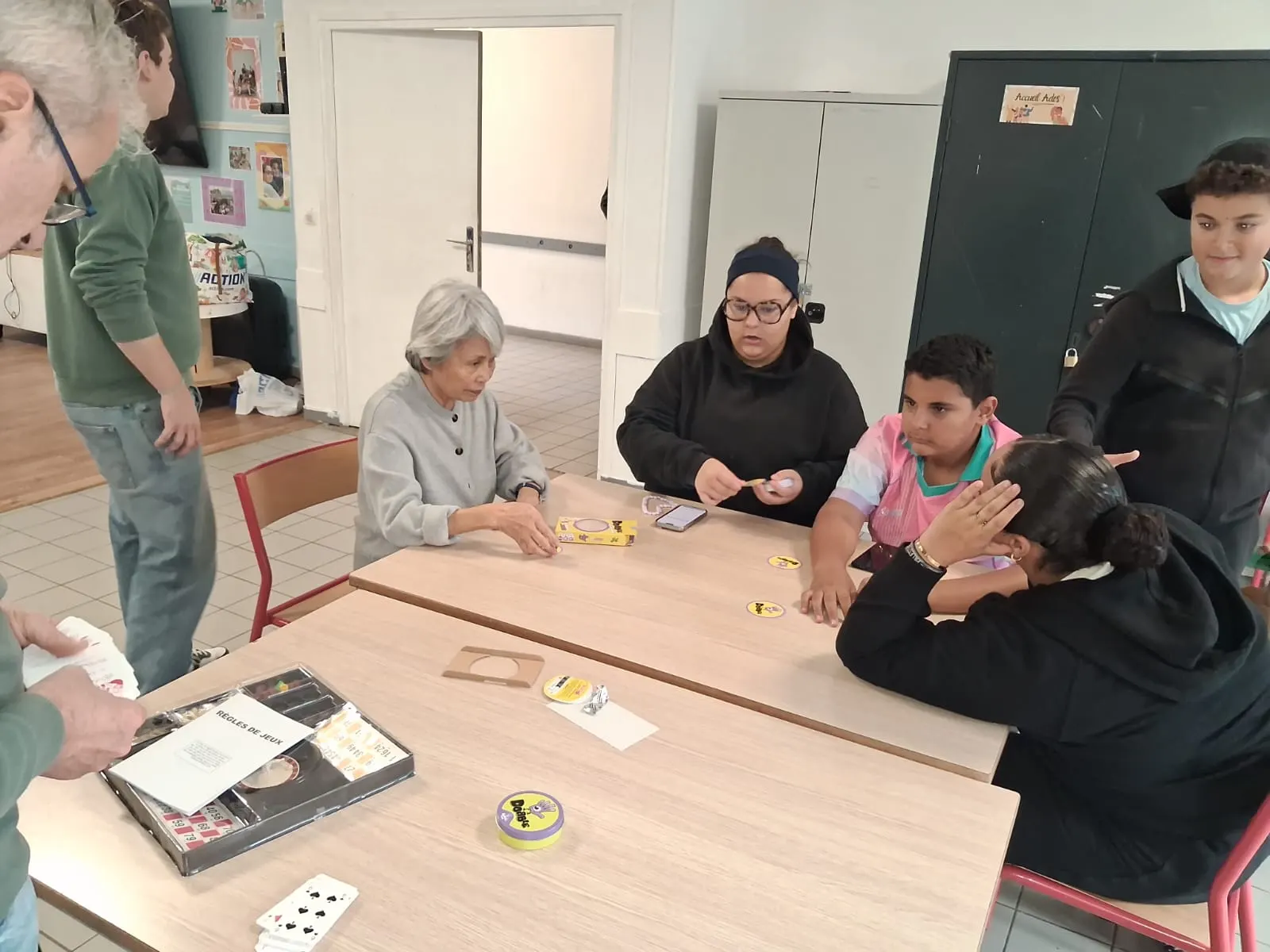 Une senior et des jeunes jouent au Dobble autour d’une table