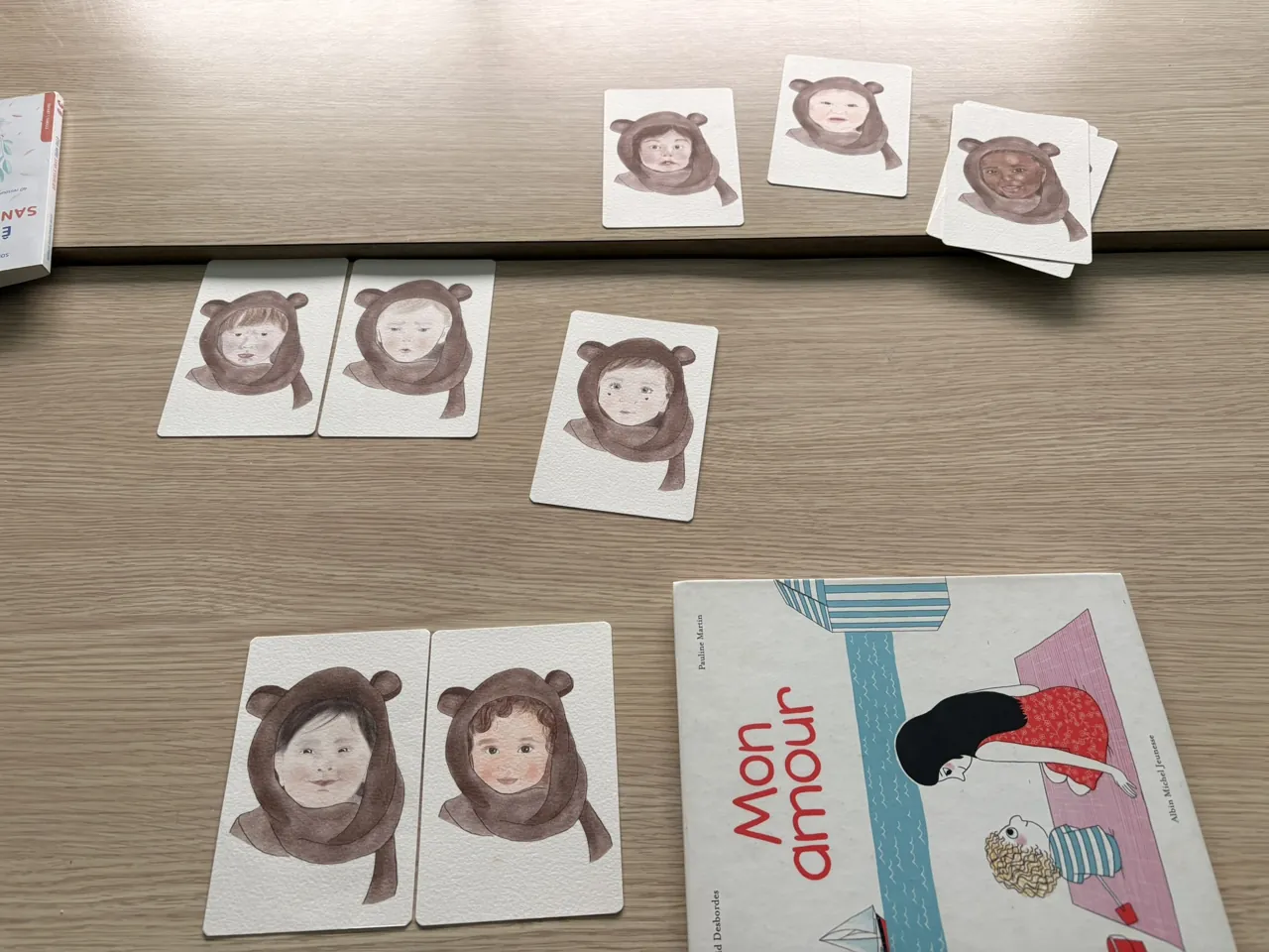 Cartes illustrées de visages de bébés et album jeunesse préparés pour un atelier avec les tout-petits