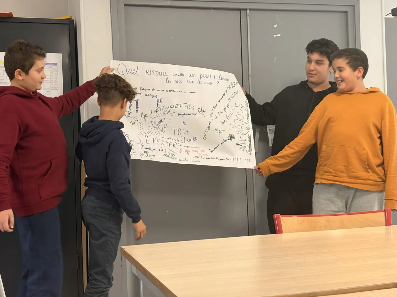Des adolescents présentent l’affiche qu’ils ont créée en atelier
