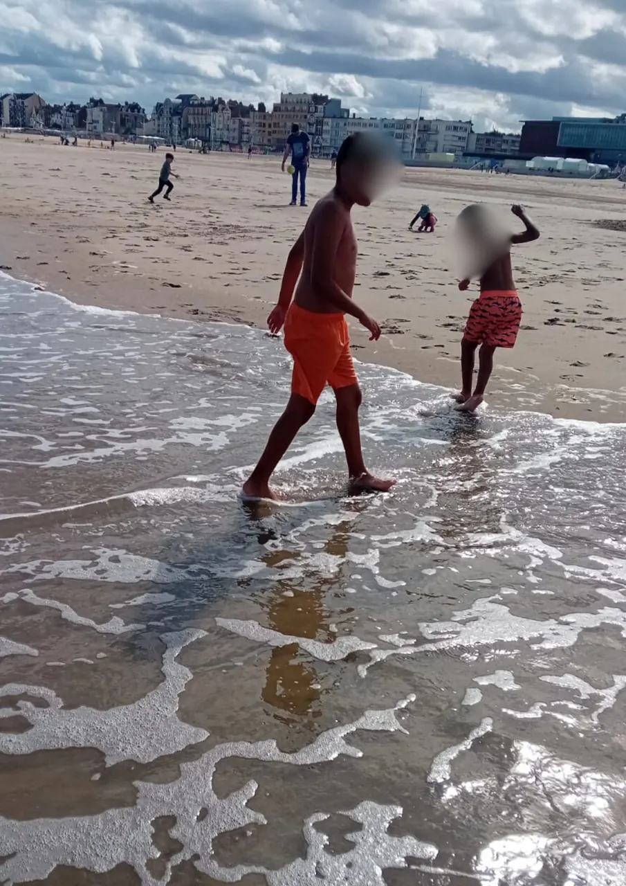 Des enfants jouent dans les vagues lors d’une sortie en famille à la plage de Malo-les-Bains